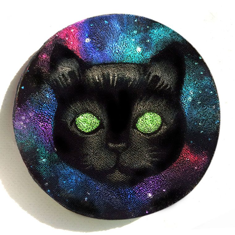 Coaster: Space Kitty. A black cat's face with glowing green eyes against a starry galaxy of pink, purple, blue and teal, painted on round black velvet.